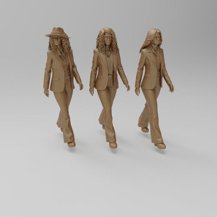 Three unpainted terracotta resin 3D printed figures of 1970s women in suits walking, for model dioramas.