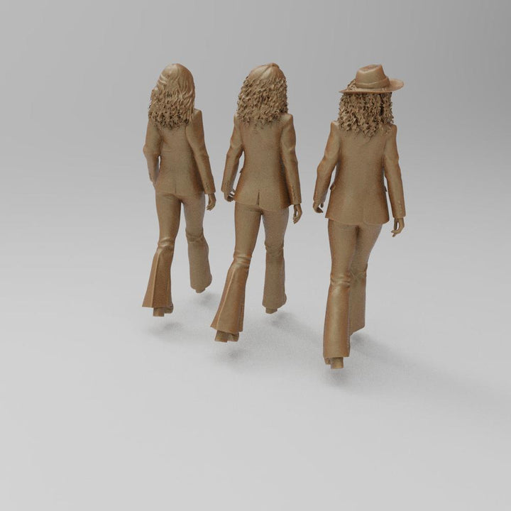 Three unpainted terracotta resin 3D-printed miniature figures of women in 1970s flared trousers and curly hair.