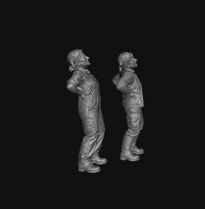 Two unpainted grey resin 3D-printed miniature figures of female farmers standing with hands on their aching backs.