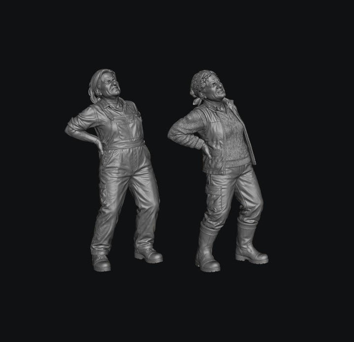 Two grey 3D-printed miniature figures of female farmers wearing work clothes and holding their aching backs.