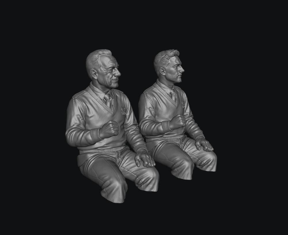 Two unpainted grey resin 3D-printed male bus driver figures in seated poses for scale model dioramas.