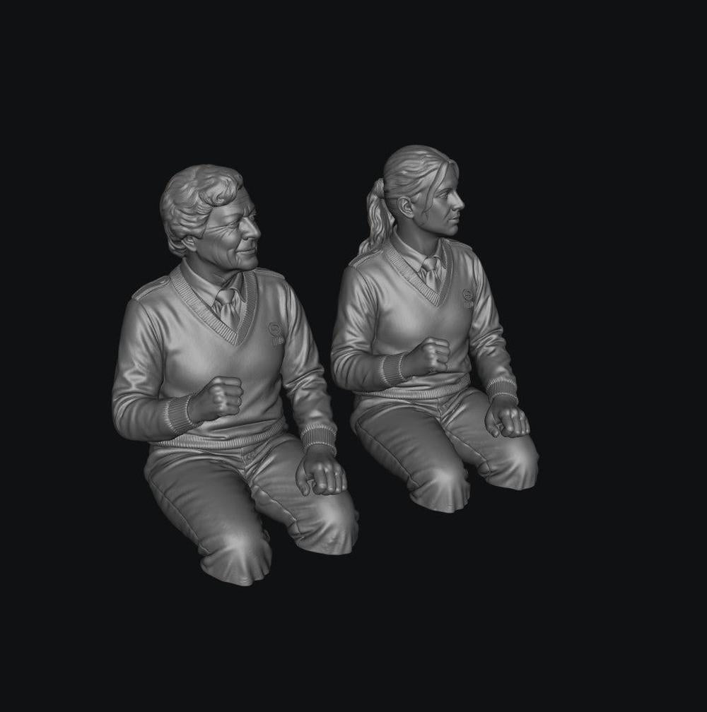 Two unpainted grey resin 3D-printed scale model figures of female bus drivers wearing V-neck sweaters and shirts.