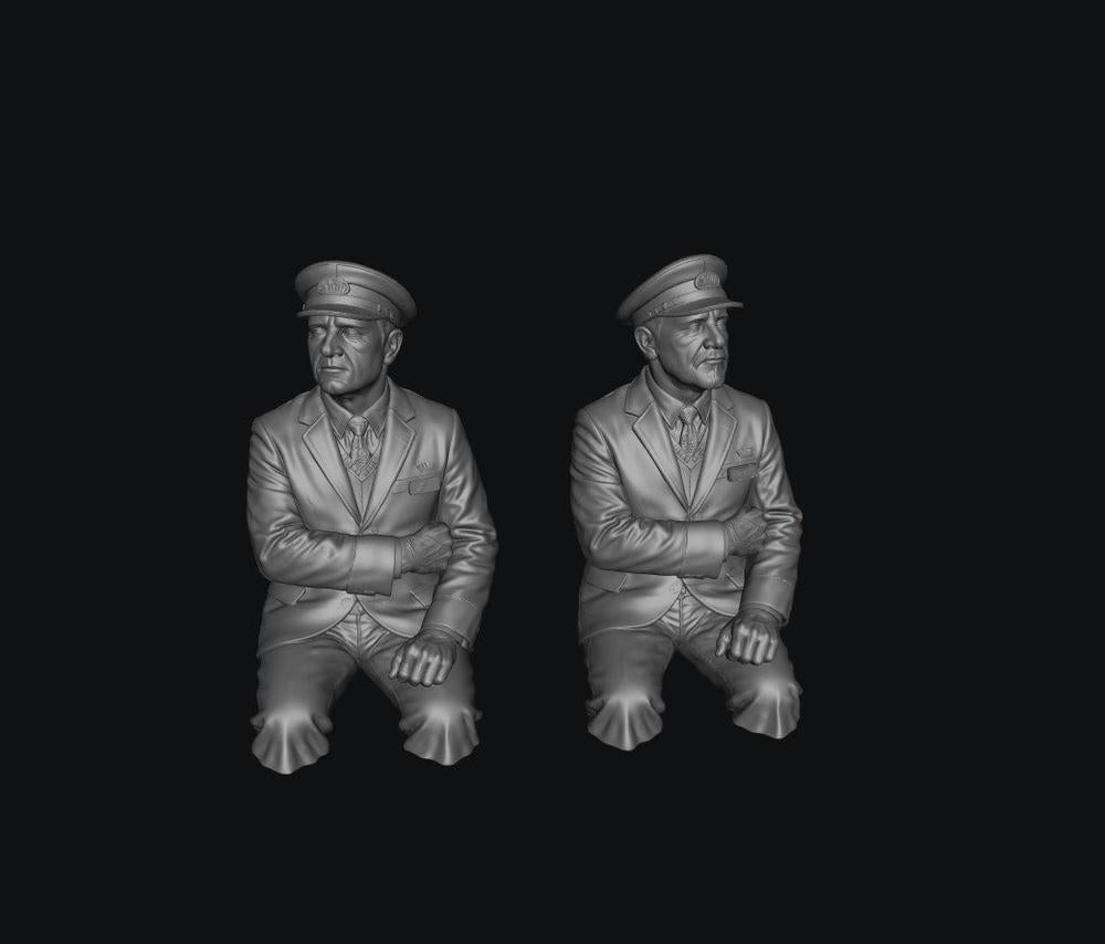 Two unpainted grey resin 3D-printed scale model train drivers wearing formal uniforms and peaked caps.