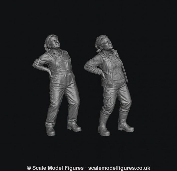 Two grey 3D-printed miniature figures of female farmers wearing work clothes and holding their aching backs.